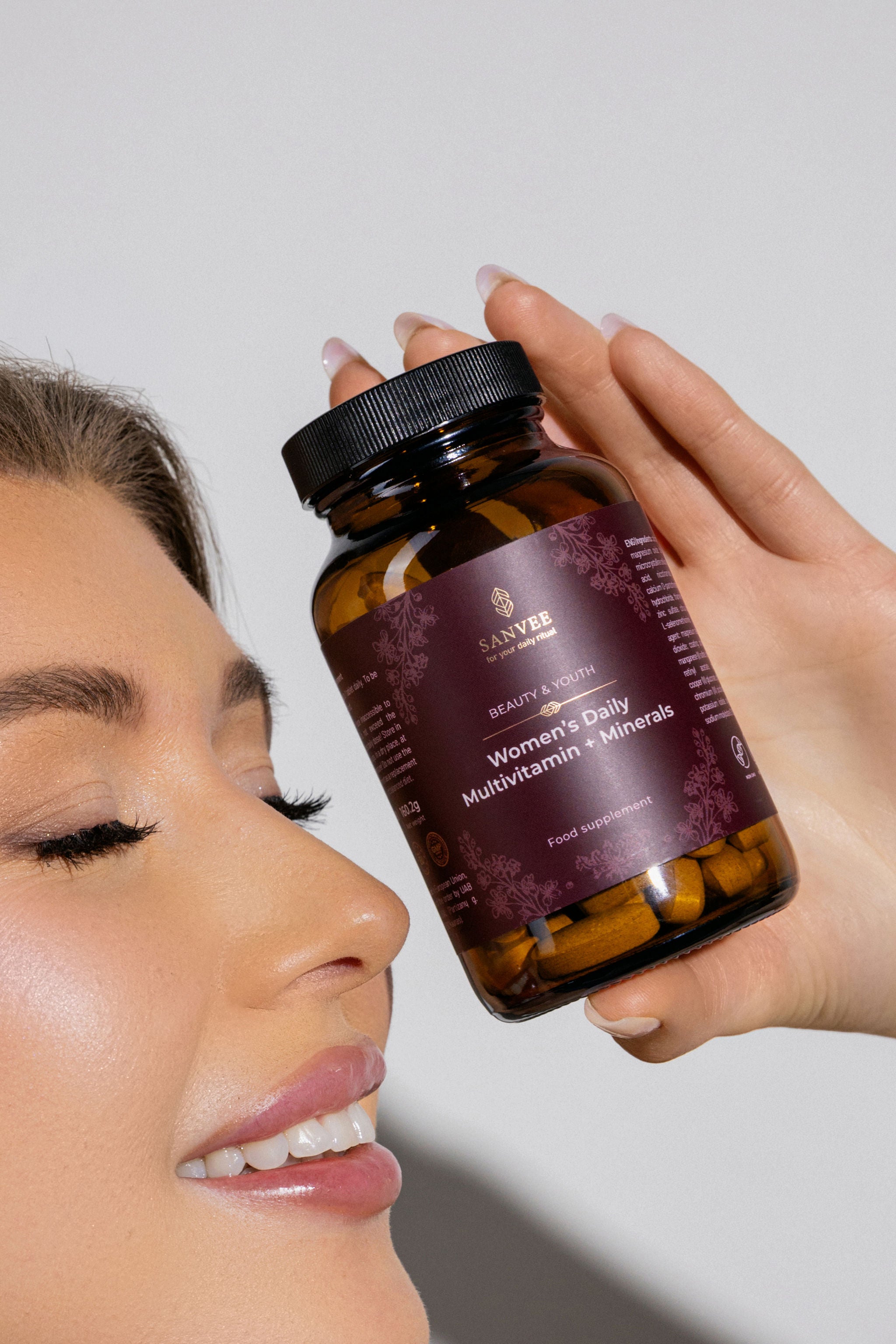 Woman holding Sanvee women's daily multivitamin bottle close to face