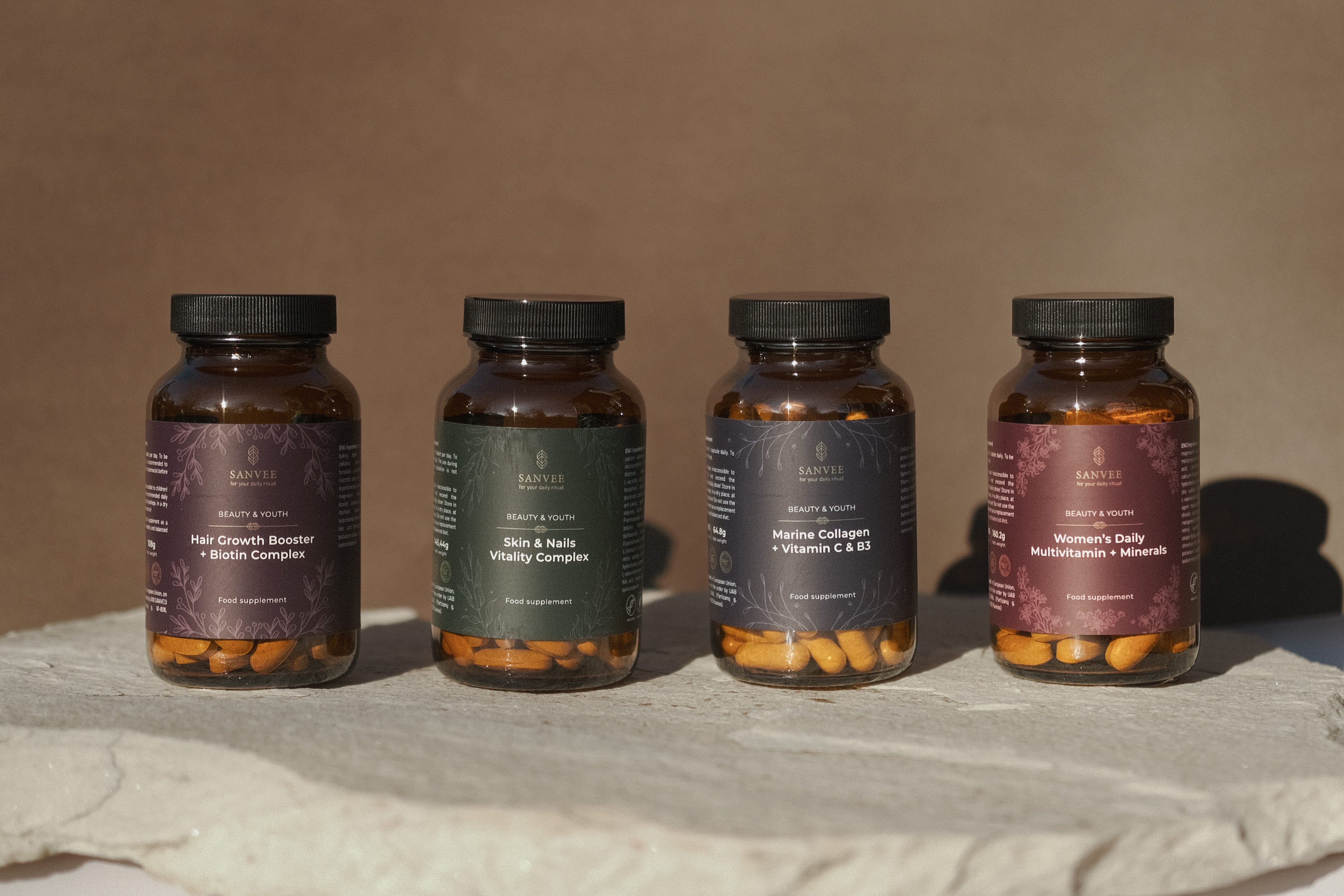 Sanvee supplement collection including hair growth biotin skin and nails collagen and multivitamin bottles on stone surface